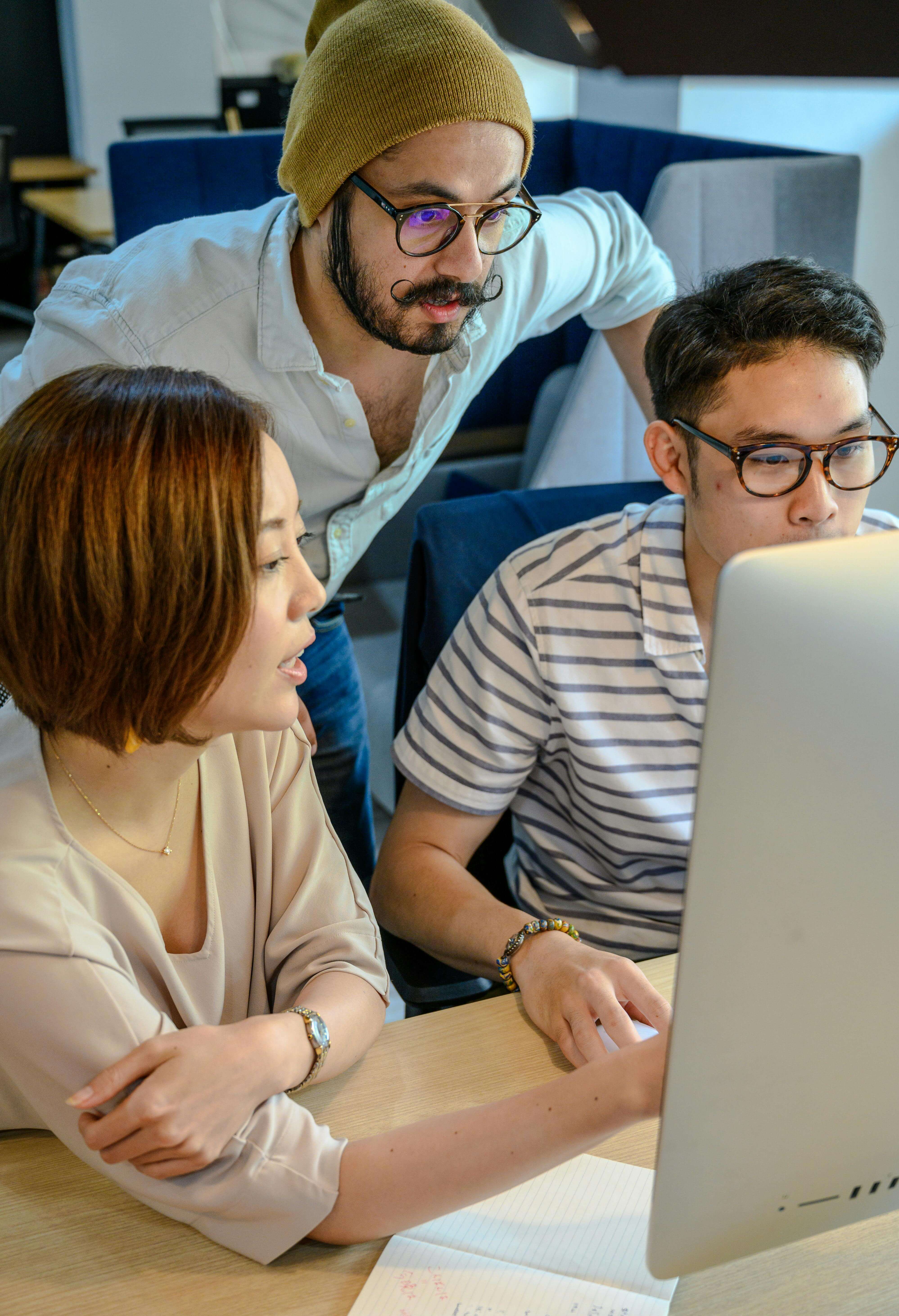 Three diverse engineers — a woman and two men — collaborating around a laptop in a modern office.